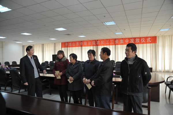 仪式上,汝州市陵头乡村十组村民杨增奇从中院副院长赵鹏举手中接过